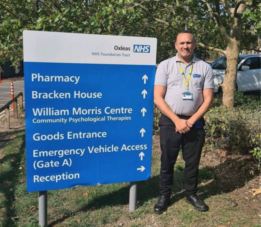 One of our NHS support staff standing next to directional board